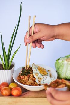 Appetizing food with chopsticks, fried egg, and vegetables on a wooden table.