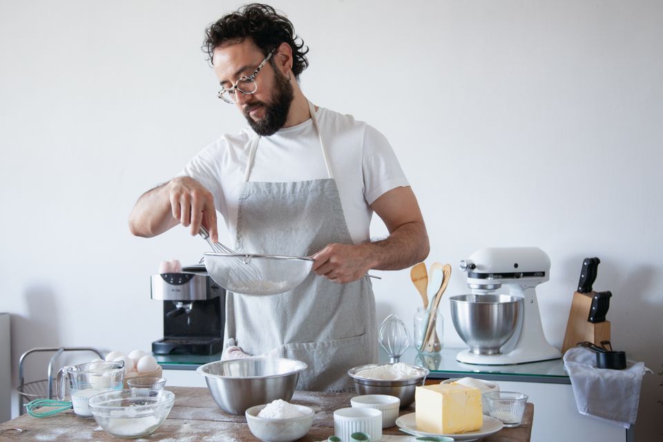 A man in an apron baking at home in his kitchen