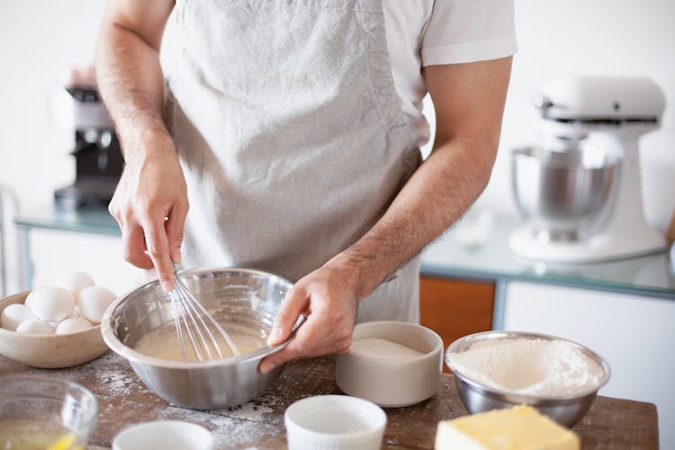 A Person Mixing A Batter Using A Wire Whisk