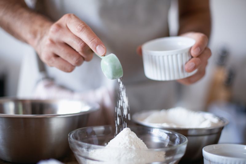 Close-up of hands measuring ingredients in a kitchen for baking.