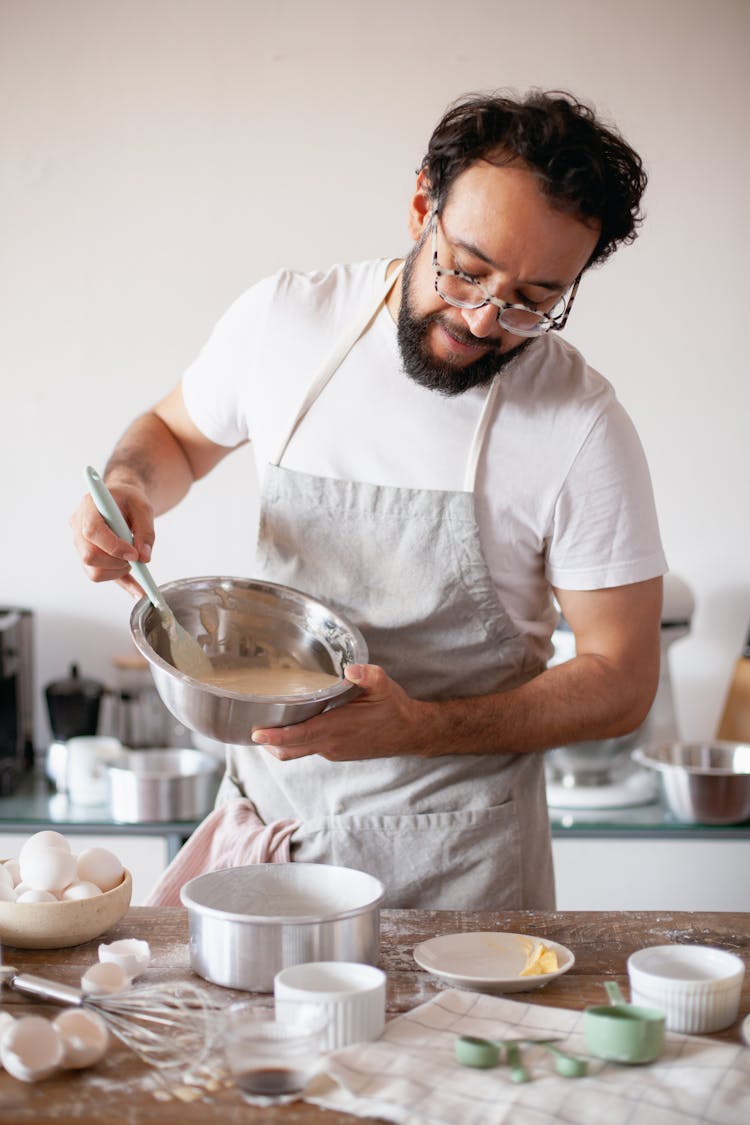 A Baker Pouring Batter Into A Baking Pan