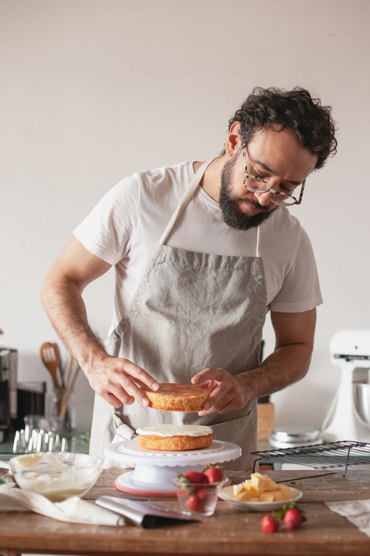 A Man Assembling A Cake