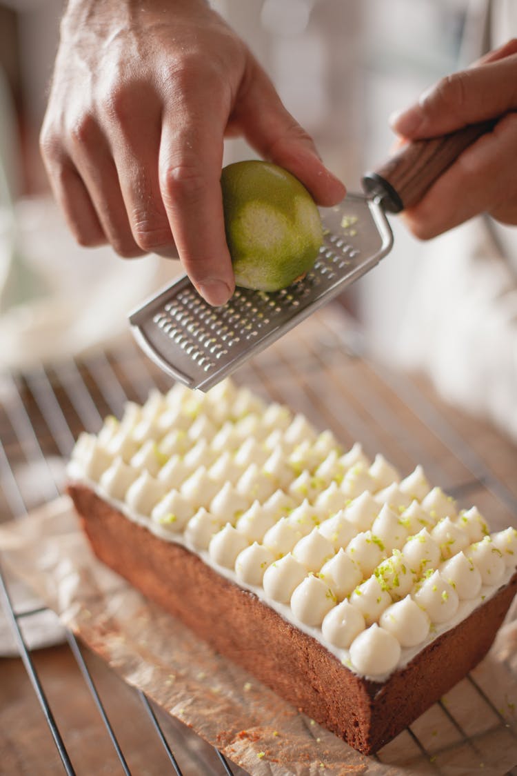 Person Putting Lime Zest On A Cake