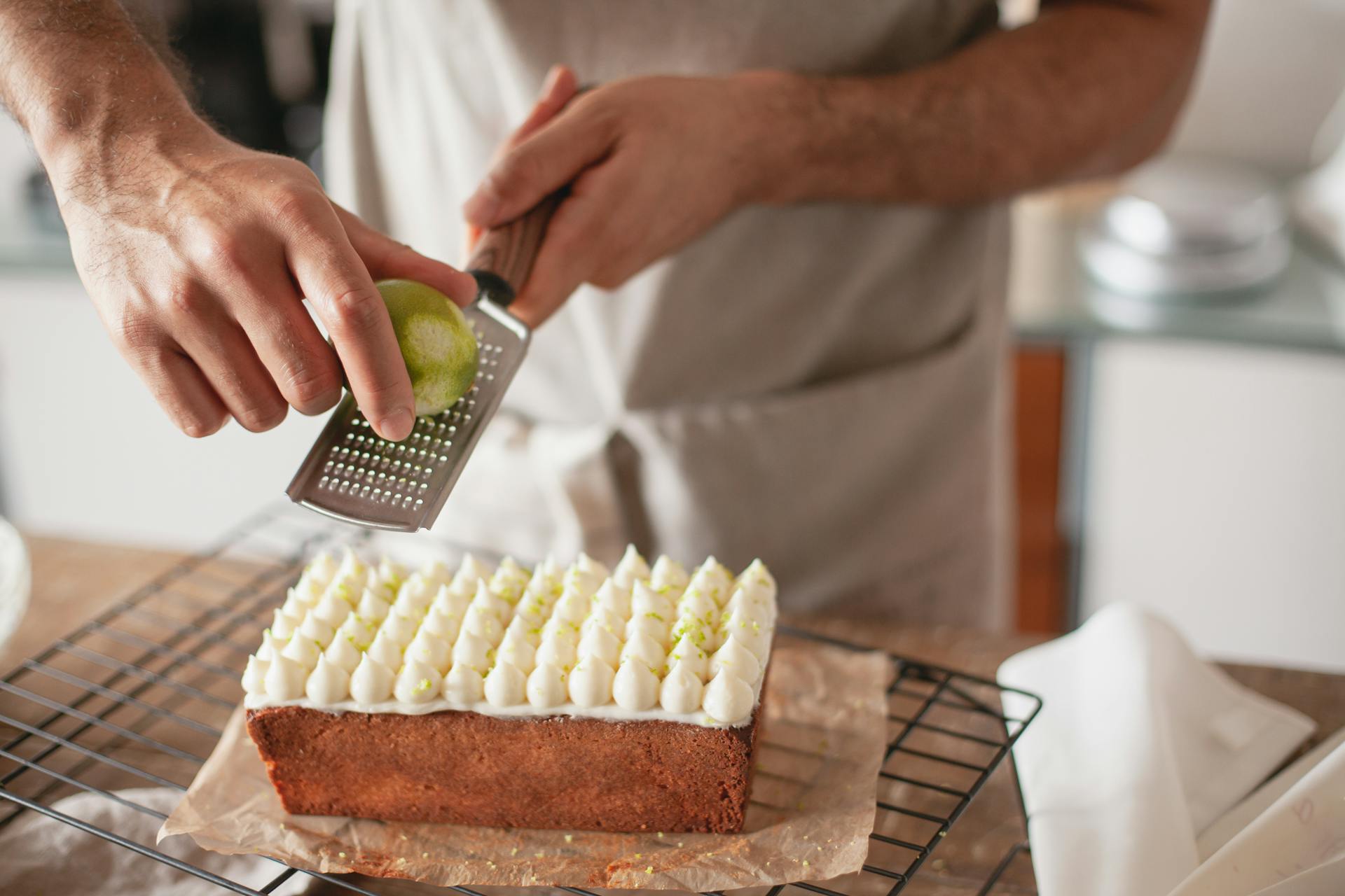 Close-up of a Person Grating Lemon Zest over a Cake