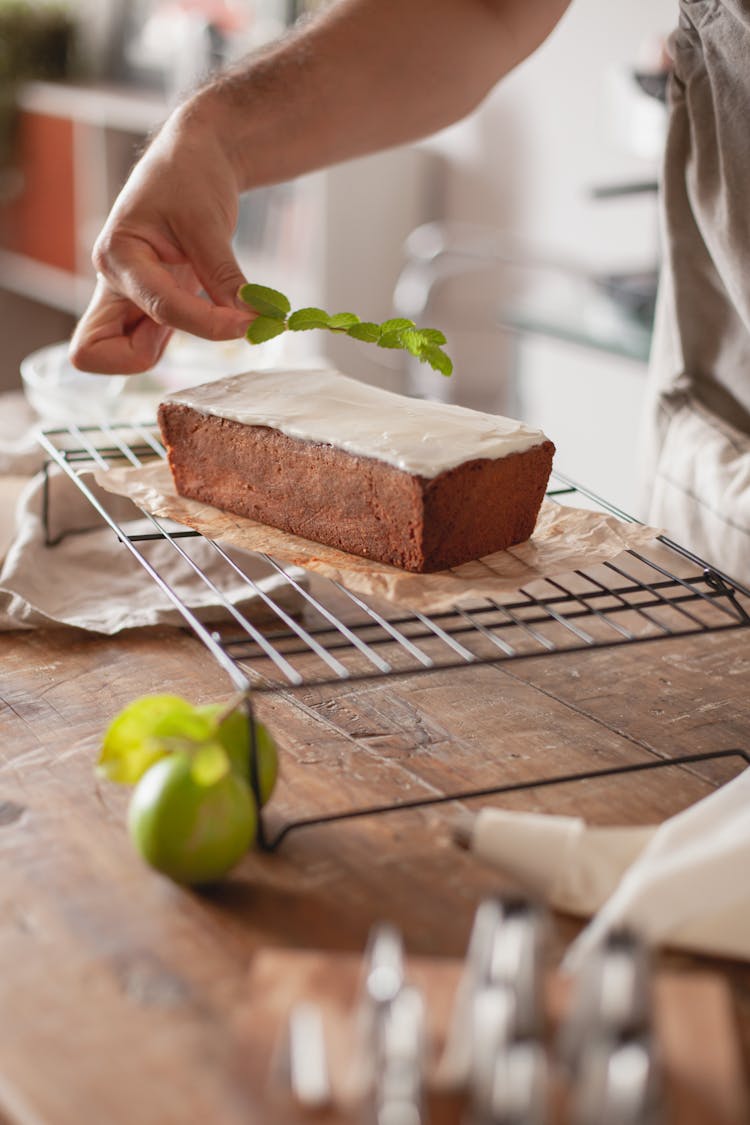 A Person Placing A Sprig Of Mint Leaves On Top Of A Cake