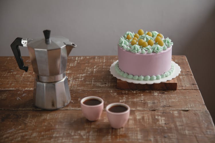 A Cake And Cups Of Coffee On A Wooden Table Top