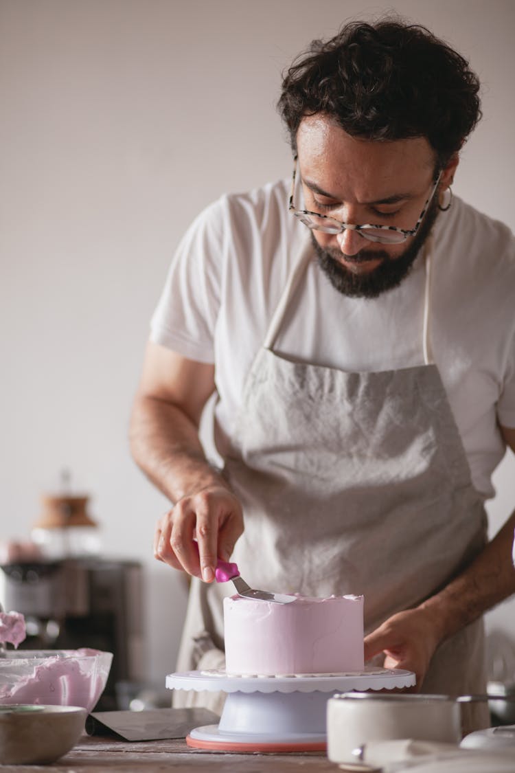 A Man Using A Spatula On A Cake