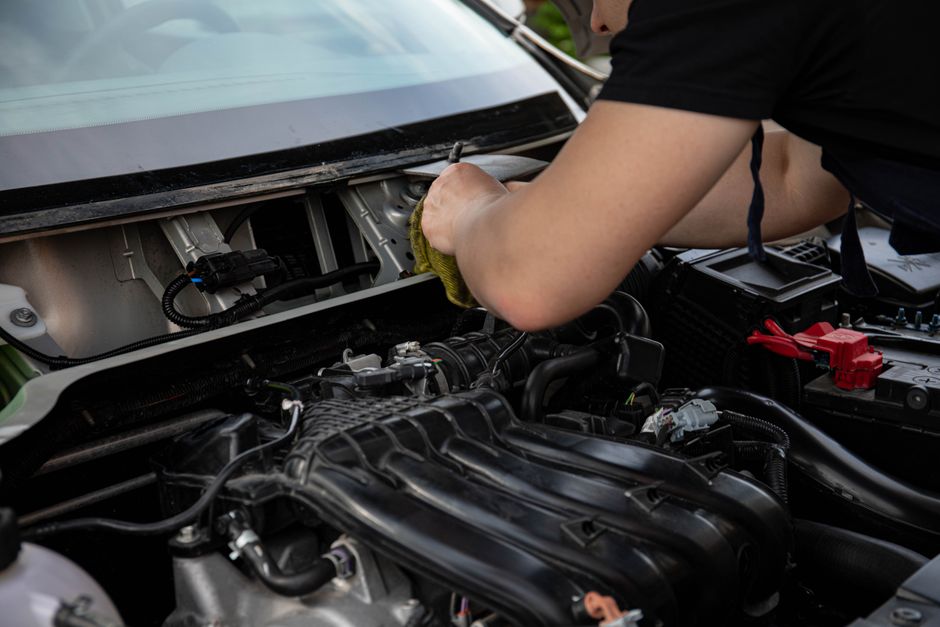 Miljöbild – A close-up of a mechanic working on a car engine in a modern auto repair shop.
