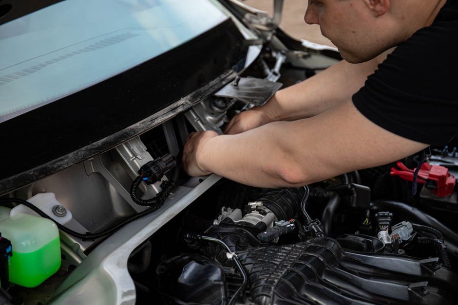 Skilled mechanic focused on repairing a car's engine in a detailed close-up shot.