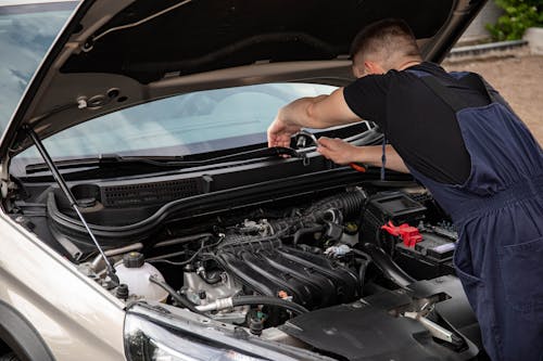 Man in Black Crew Neck T Shirt Using a Socket Wrench