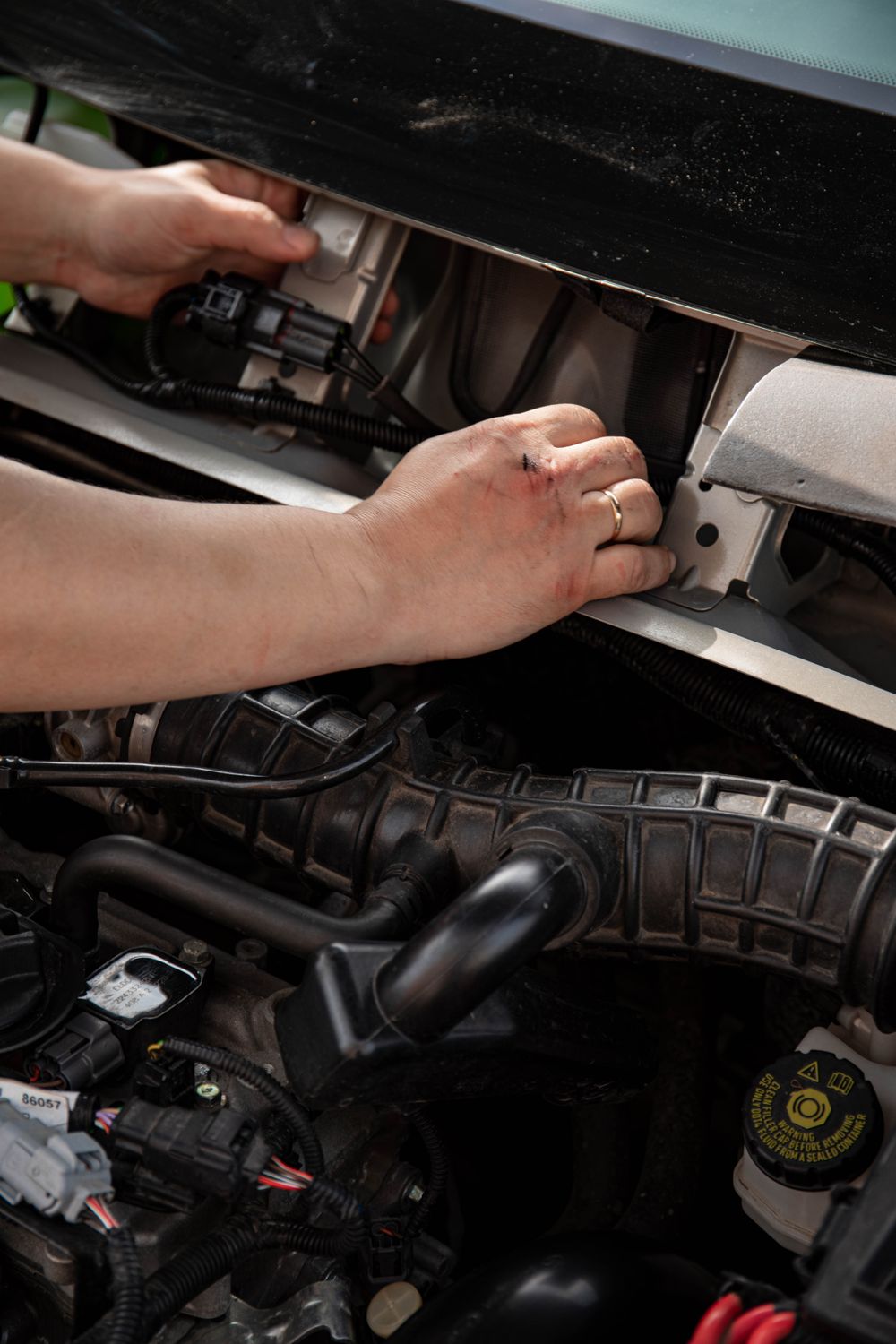 Hands working on an engine bay part