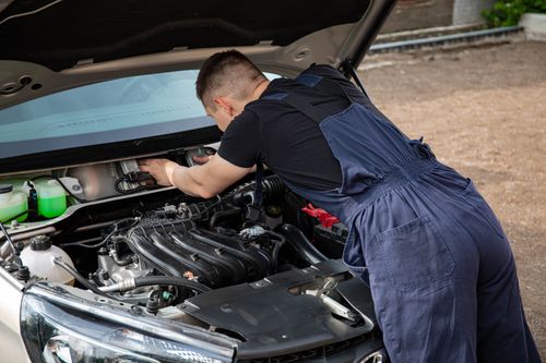 Free Mechanic in overalls fixing a car engine outdoors, showcasing automotive repair skills. Stock Photo
