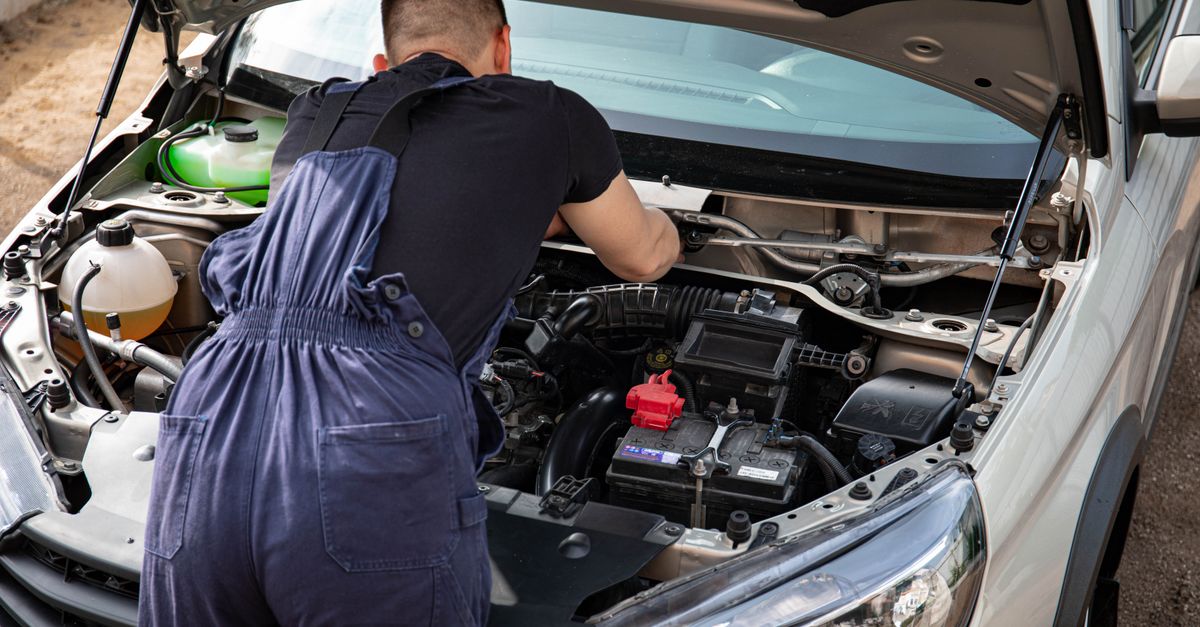 Close-up of mechanic repairing a car engine. Outdoor setting during the day.