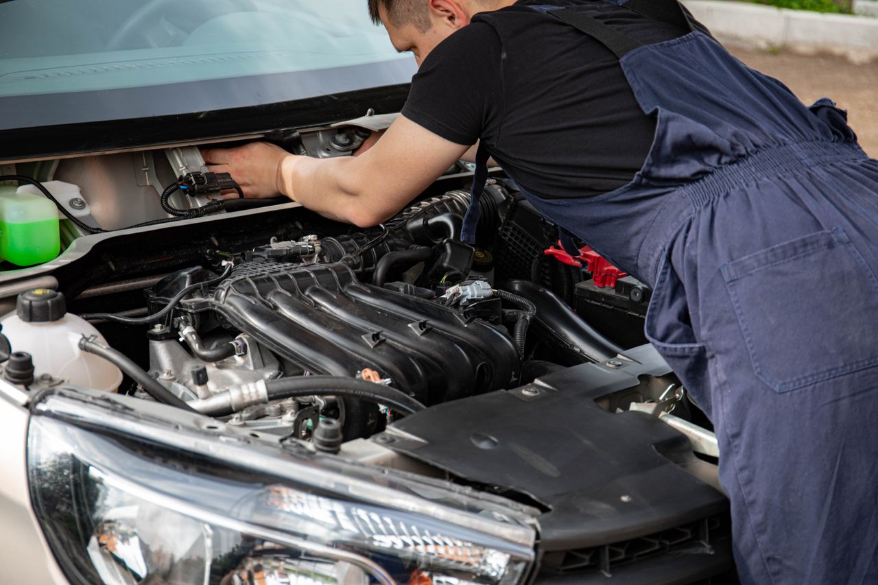 Mechaniker im Arbeitsbereich vor einem geöffneten Fahrzeug.
