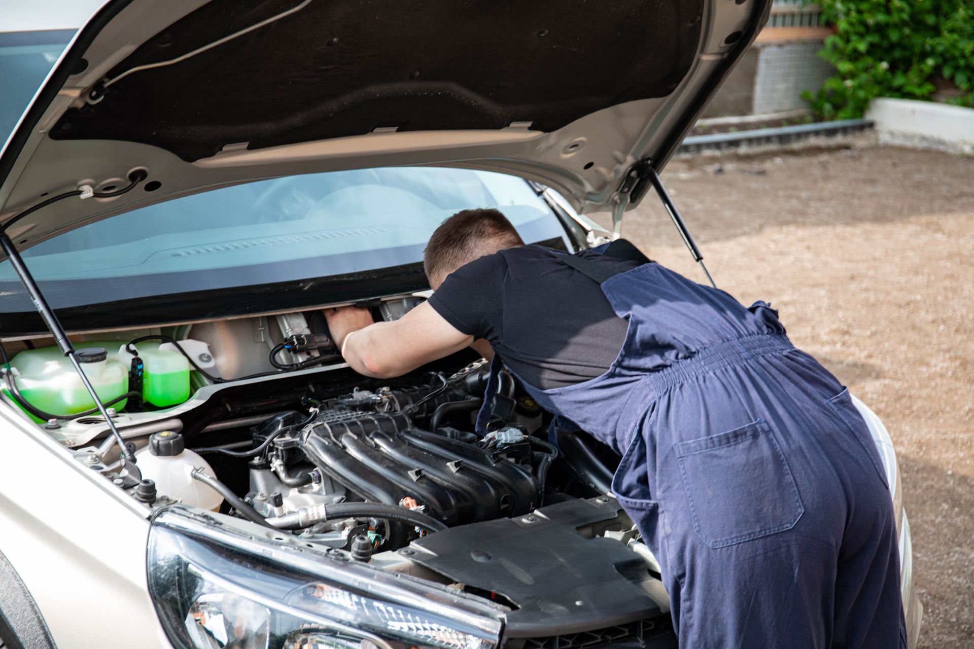 Techniker arbeitet konzentriert im Motorraum eines Fahrzeugs in der Werkstatt.
