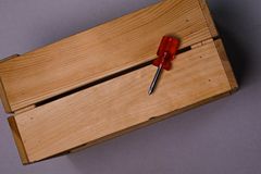 A minimalist image of a wooden box with a red-handled screwdriver, perfect for DIY themes.