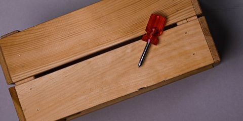 A minimalist image of a wooden box with a red-handled screwdriver, perfect for DIY themes.