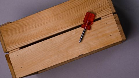A minimalist image of a wooden box with a red-handled screwdriver, perfect for DIY themes.