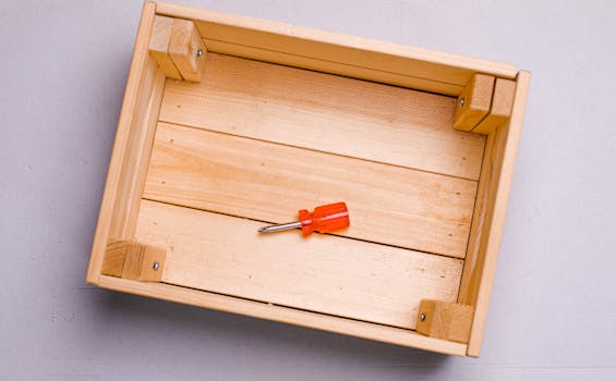 A wooden box displaying a red screwdriver on a grey background.
