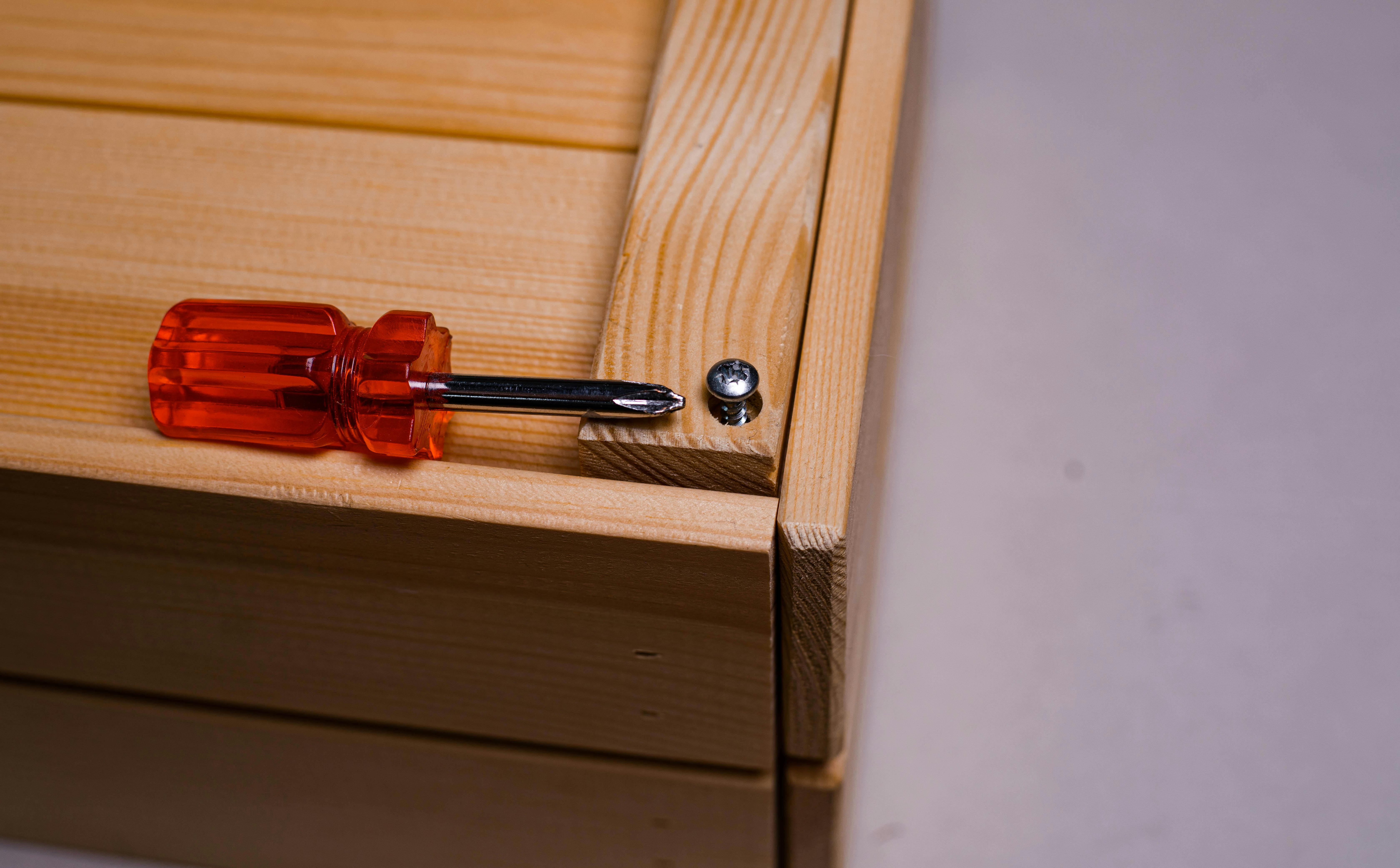 red and silver screwdriver on brown wooden box