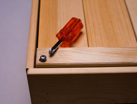 Close-up view of an orange screwdriver on wood, highlighting carpentry work.