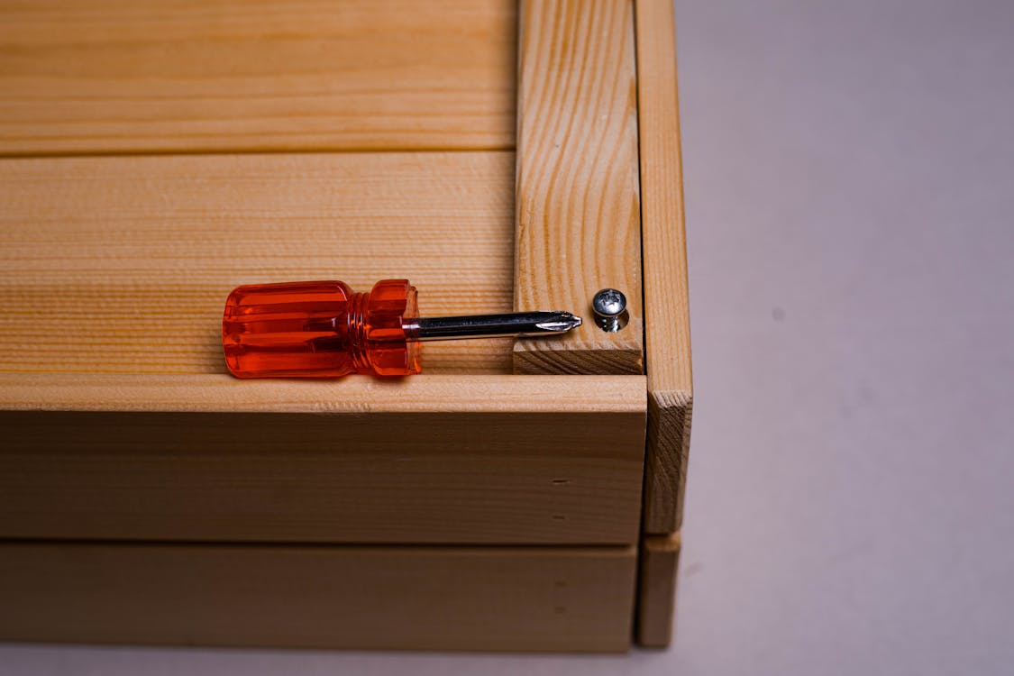 Red and Silver Screwdriver on Wooden Surface 