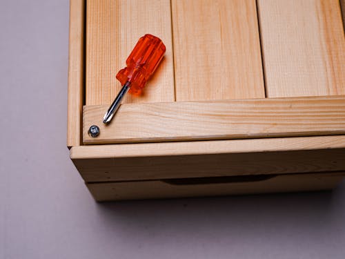 Red and Silver Screwdriver on Wooden Surface 