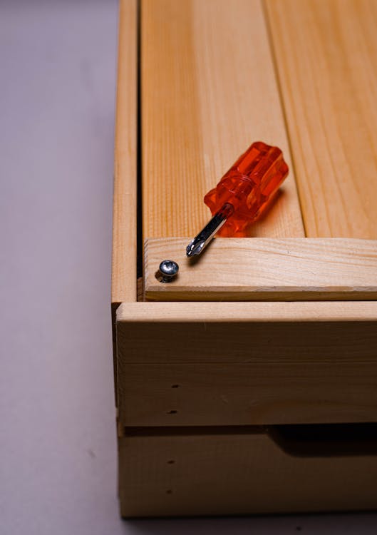 Red and Silver Screwdriver on Wooden Surface 