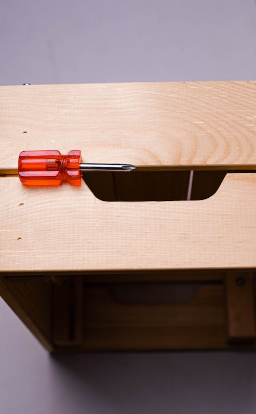 Red and Silver Screwdriver on Wooden Box