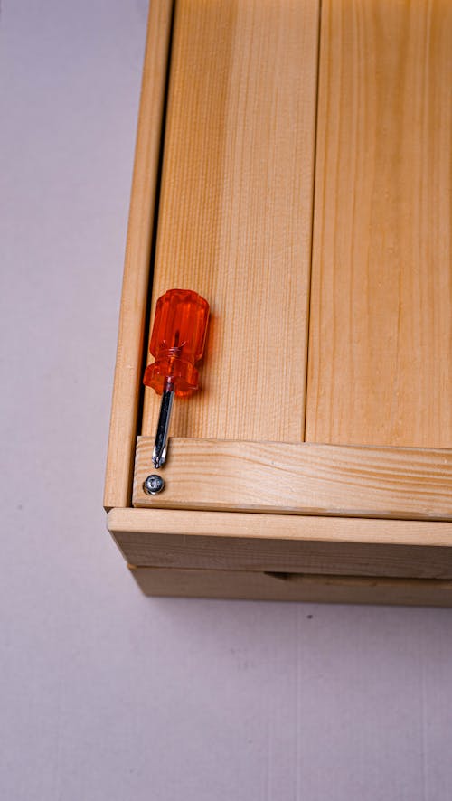 Red and Silver Screwdriver on Wooden Surface 