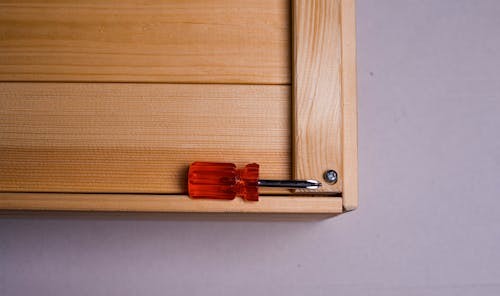 Red and Silver Screwdriver on Wooden Surface 