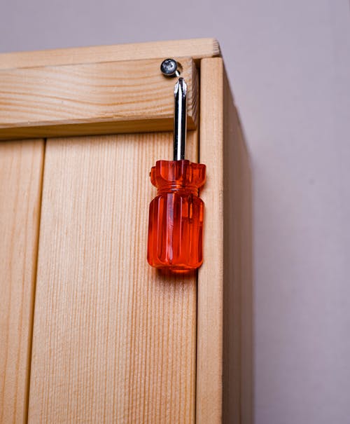 Red and Silver Screwdriver on Wooden Surface 