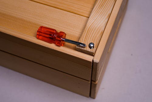 Red and Silver Screwdriver on Wooden Surface 