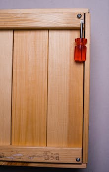 Detailed view of an orange screwdriver on a light wooden panel, showcasing minimalism and craftsmanship.