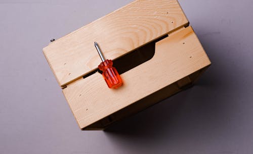 Red and Silver Screwdriver on Wooden Box