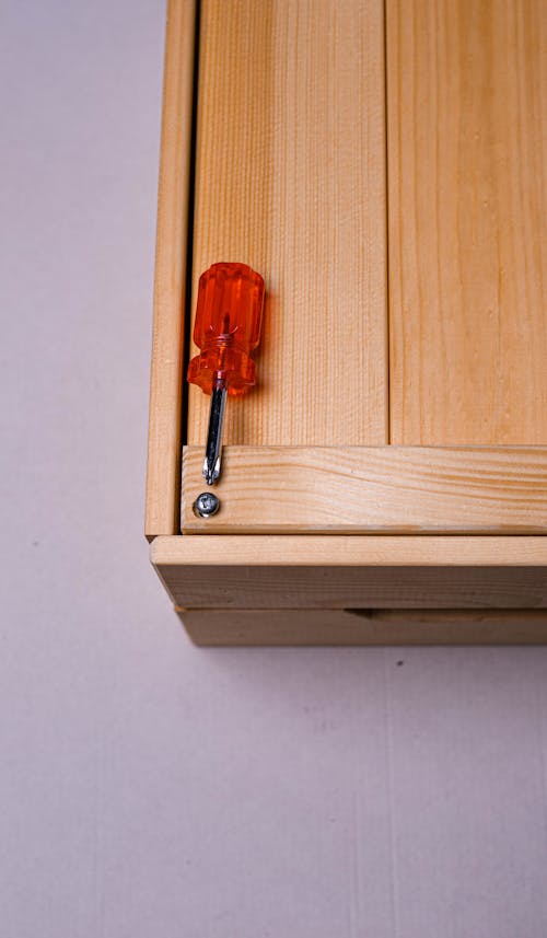 Red and Silver Screwdriver on Wooden Surface 