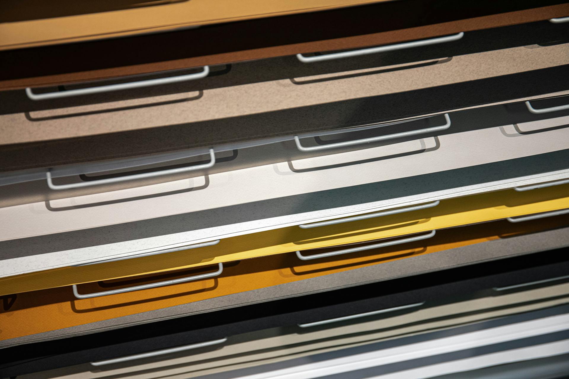 Close-up of colorful metal drawers filled with various colored paper sheets under bright lighting.