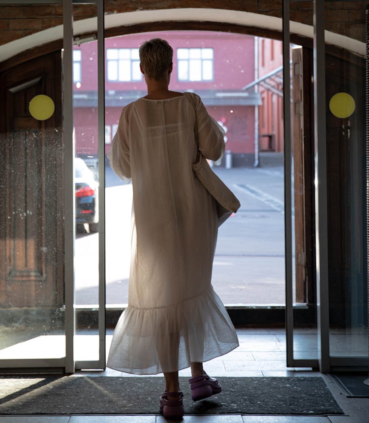 Woman In White Dress Walking Through Glass Doors