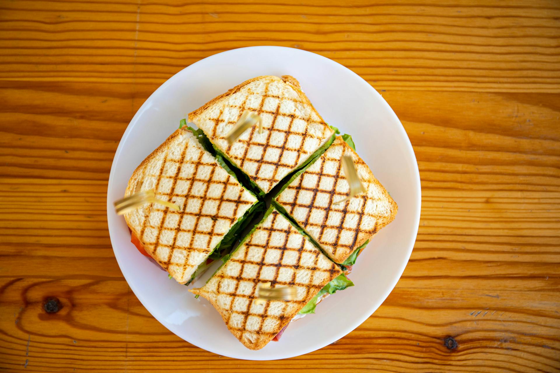 Delicious grilled sandwich with crispy lines, cut into quarters and served on a plate.