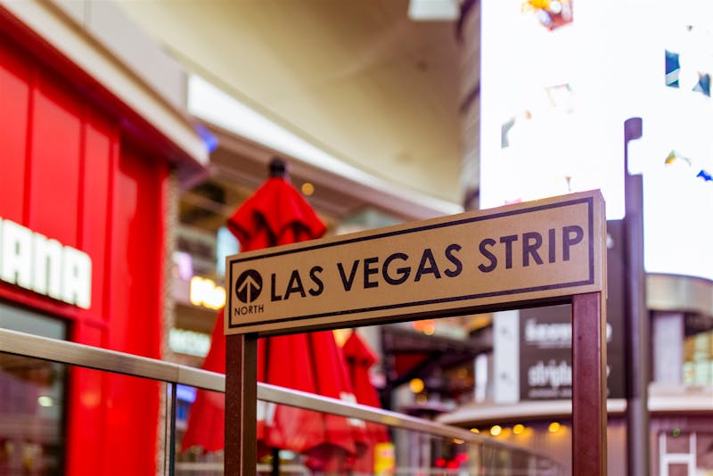 Panneau emblématique de Las Vegas Strip avec arrière-plan de vie urbaine vibrante.