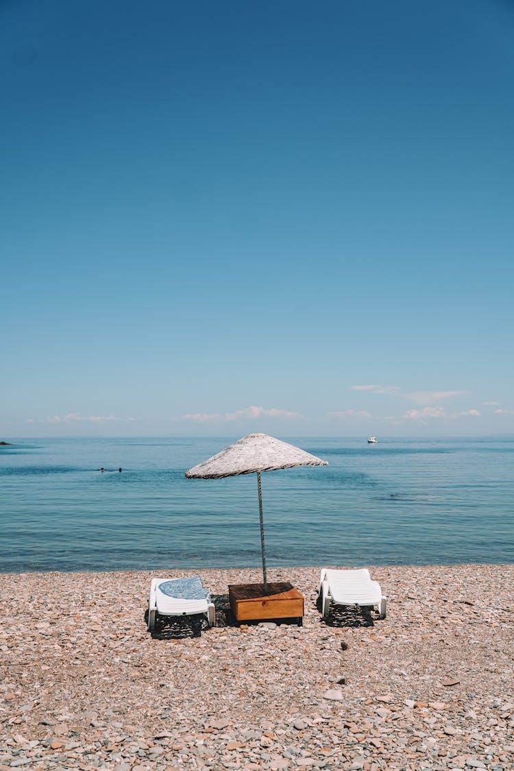Photo Of Chairs And An Umbrella At The Beach
