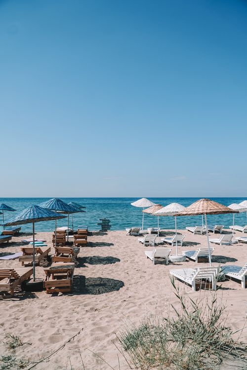 Free Sunlit sandy beach in İzmir with chairs and umbrellas for relaxation. Stock Photo