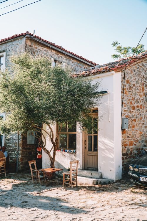 Free A quaint stone building with outdoor seating in Gökçeada, Türkiye, under a sunny sky. Stock Photo
