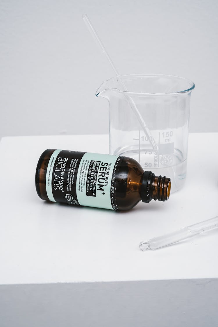 Close-up Of A Bottle Of Hair Serum And A Beaker