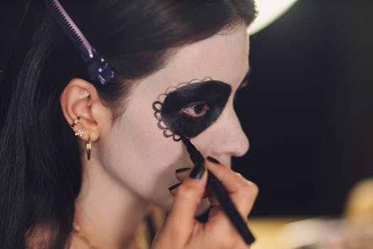 Close-up of a woman applying Day of the Dead makeup, showcasing intricate design and artistry.