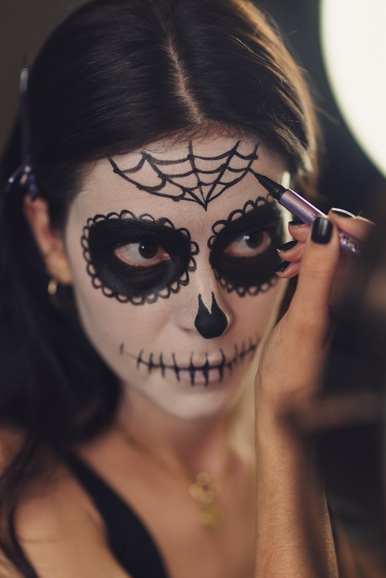 A Woman Drawing A Cobweb On Face Using An Eyeliner