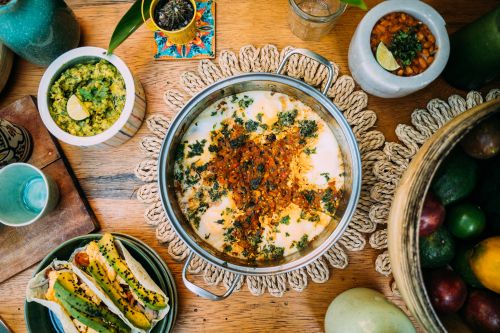 Free Colorful Mexican dishes with guacamole, tacos, and beans on a wooden table. Stock Photo