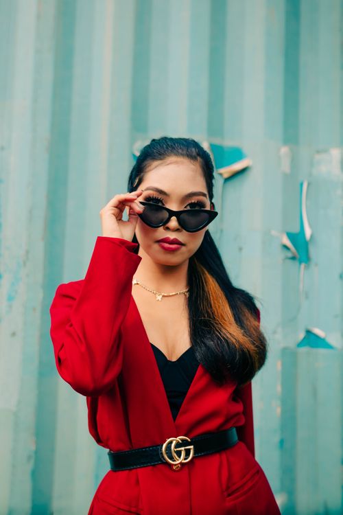 Free Fashionable woman in red blazer wearing sunglasses in urban setting. Stock Photo