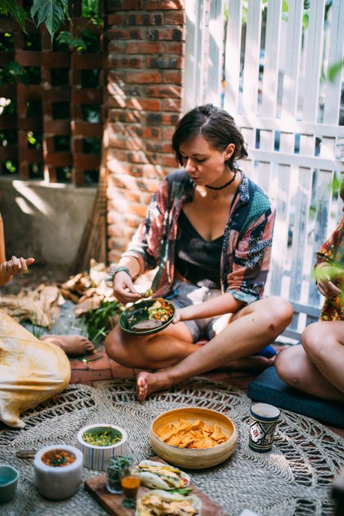 Free Friends sitting outdoors enjoying a colorful picnic with Mexican food under leafy surroundings. Stock Photo