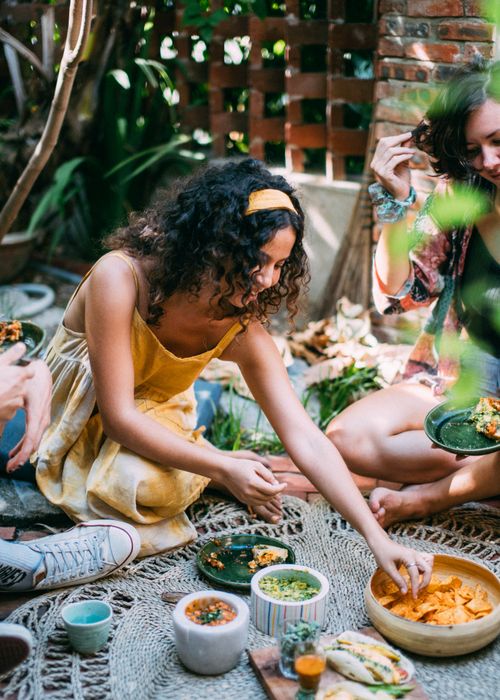 Free A group of friends enjoying a relaxed picnic outdoors with an array of delicious snacks. Stock Photo
